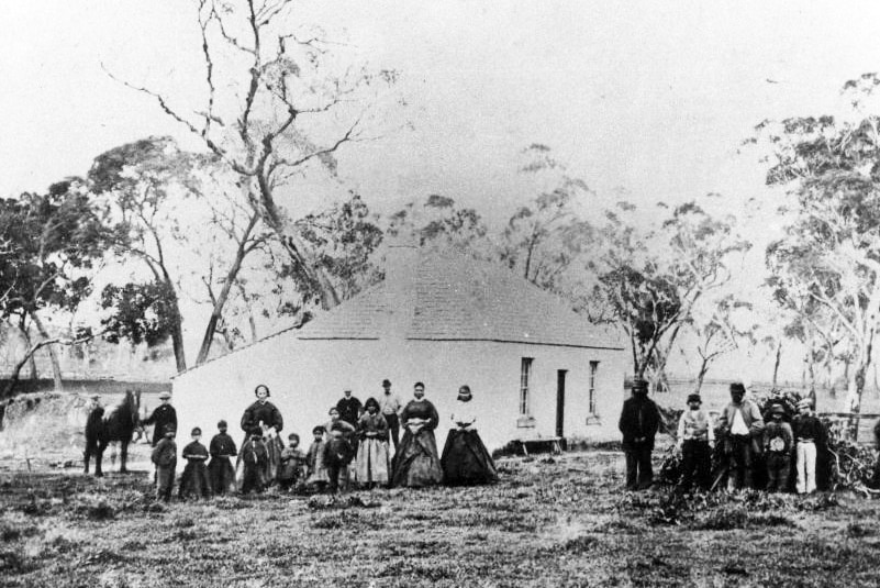 Old house with a group of people standing outside