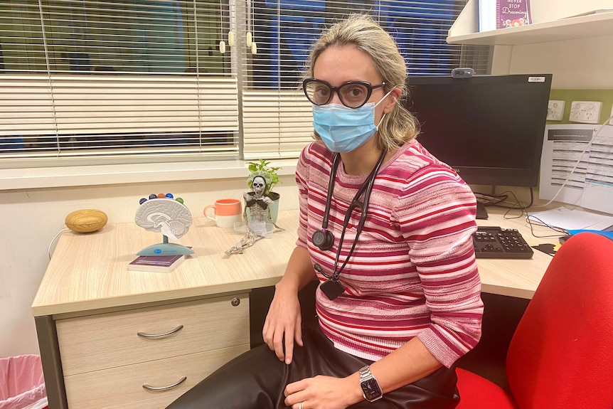 Nicca Grant sits at her desk wearing a blue face mask.