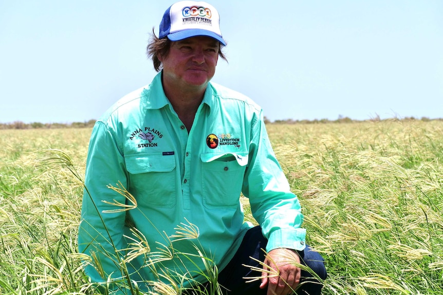 Pastoralist in green shirt kneeling in fodder