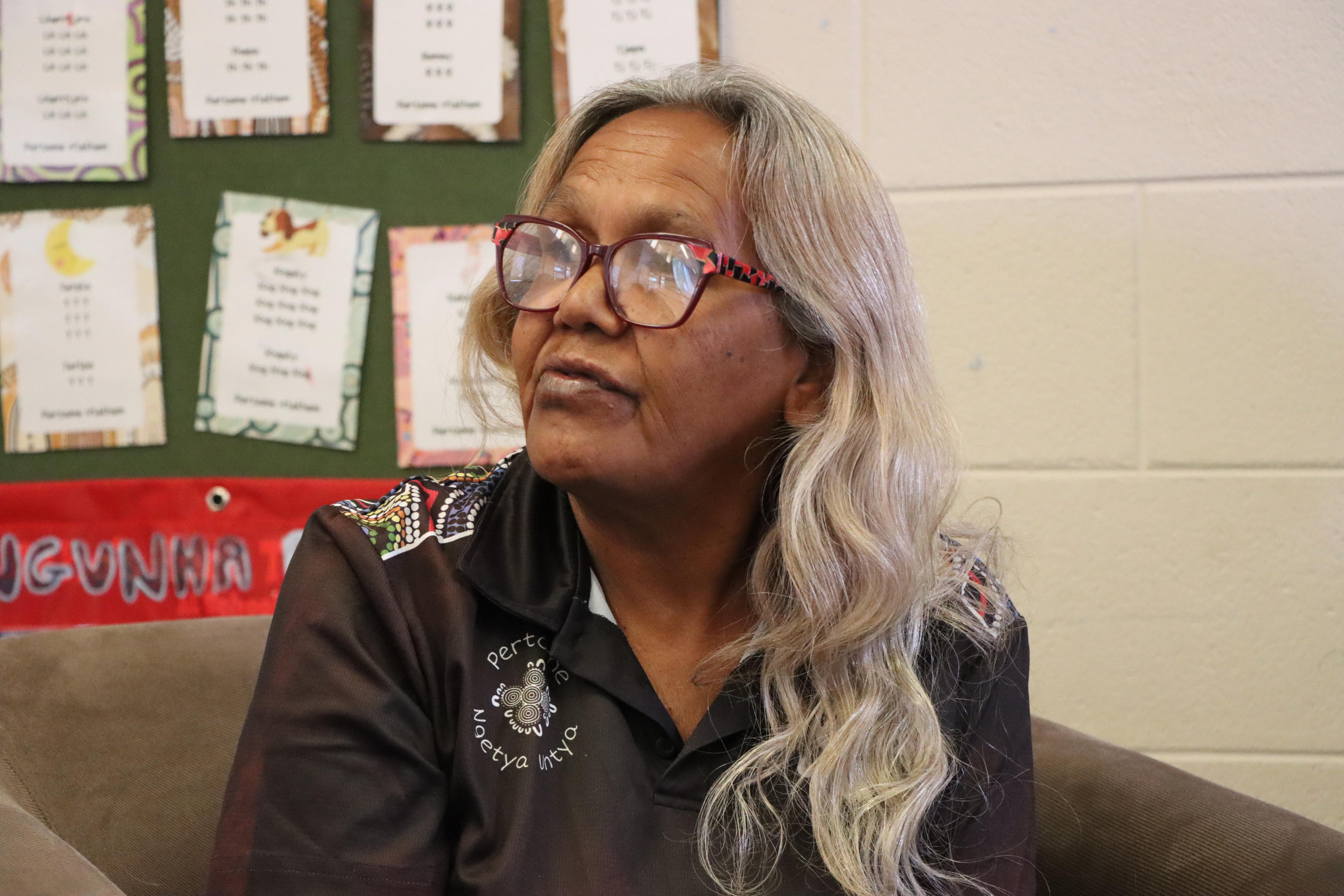 A woman with long, grey hair looks to her right.
