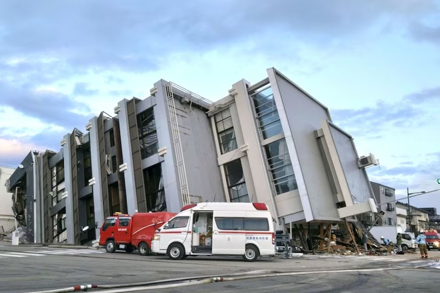 A collapsed building in the middle of a main road with cars