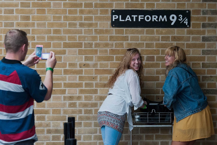 Tourists pose at Harry Potter platform at London's Kings Cross Station