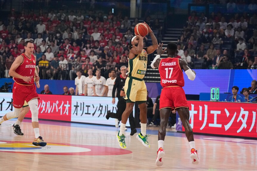 An Australian Boomers basketballer gets ready to release the ball mid-air for a three-point shot during a game.