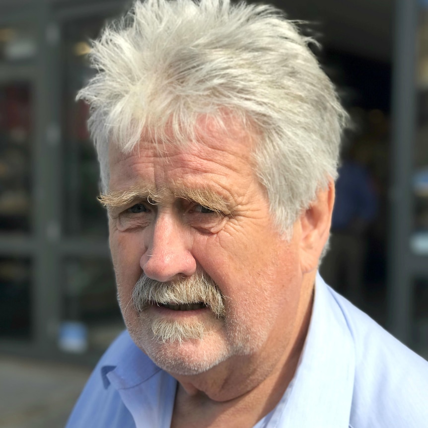 A man with a blue shirt outside on the street.