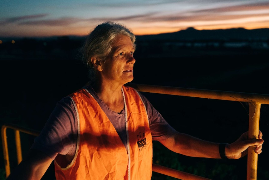 Linda Keeping with her face lit by a light on a tractor at dawn