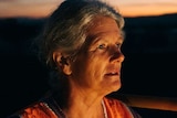 Linda Keeping with her face lit by a light on a tractor at dawn