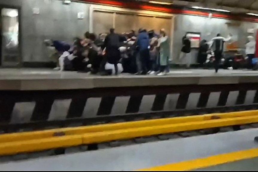 People at a metro station platform are seen fleeing and falling down.