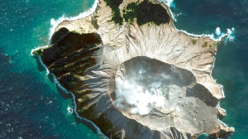 A satellite image shows a bird's eye view of a volcanic island surrounded by turquoise ocean waters.