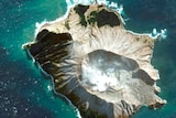 A satellite image shows a bird's eye view of a volcanic island surrounded by turquoise ocean waters.