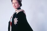 A woman faces side on while wearing a crown and a royal cape.
