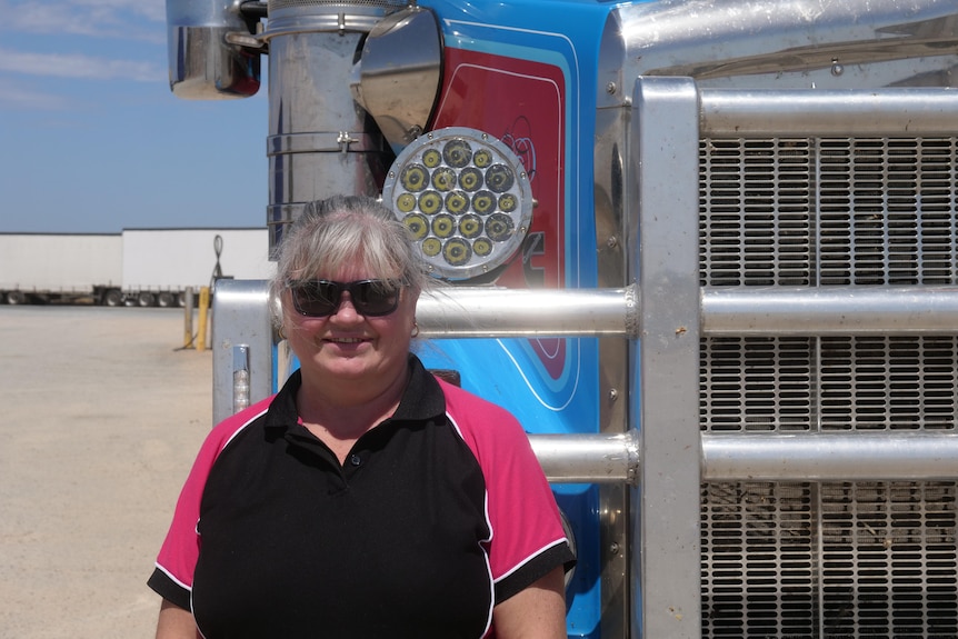 A woman in a black and pink polo in front of a truck 