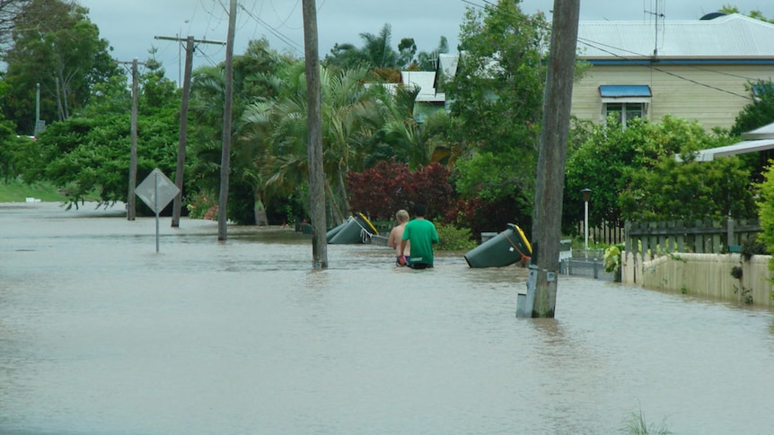 Residents wade through floodwaters at Hinkler Avenue in Bundaberg