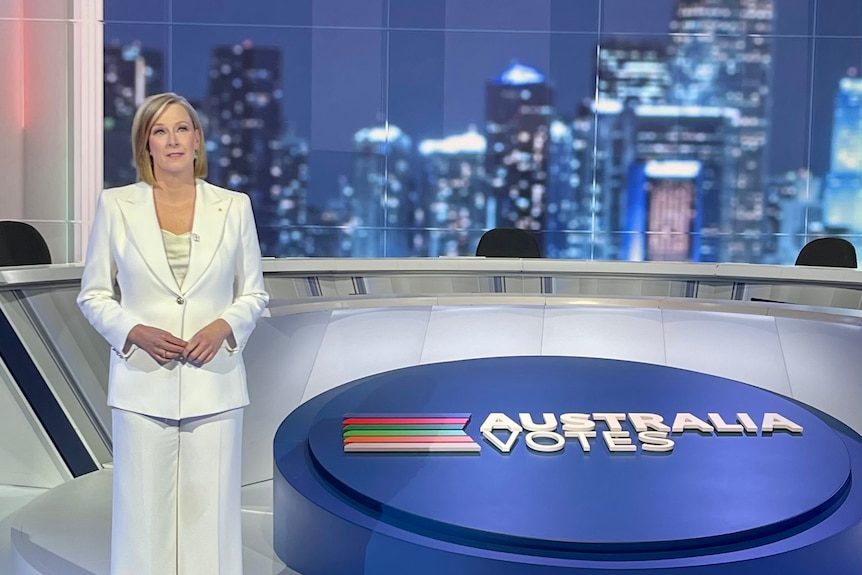 Woman standing in TV studio in front of panel and Australia Votes signage.