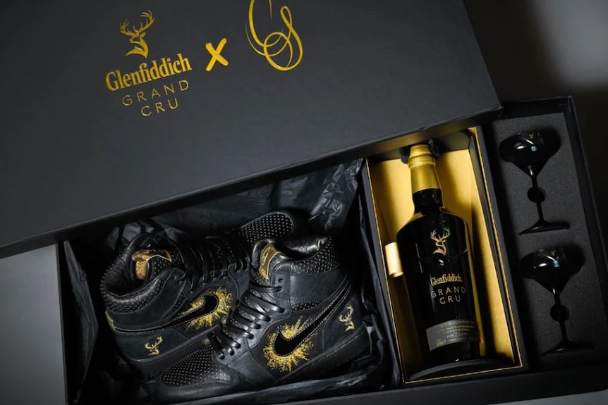 A black sneaker with a bottle of Glenfiddich whisky.
