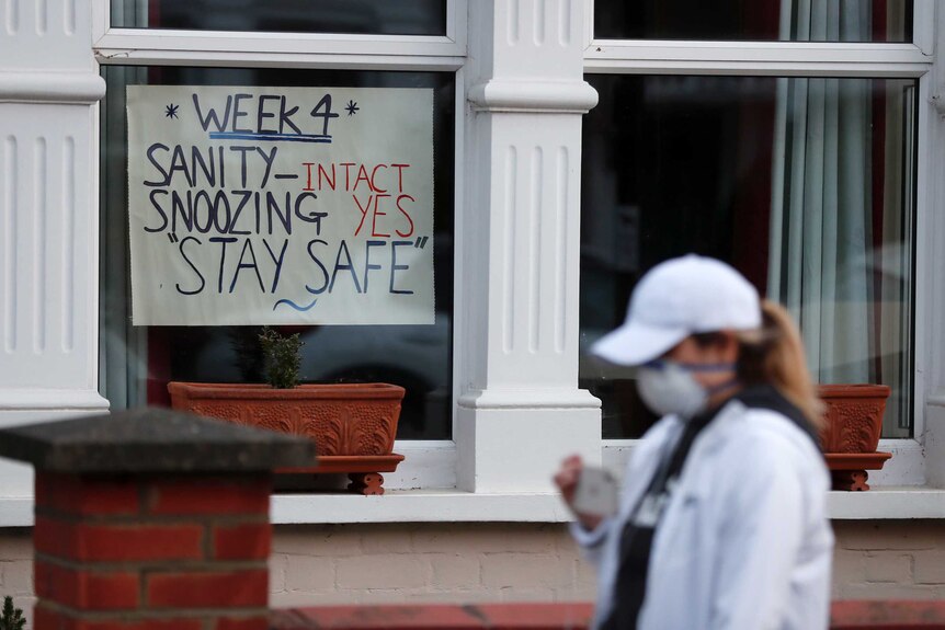 A cardboard sign in the front window of a house reads "sanity- intact, snoozing - yes, stay safe"