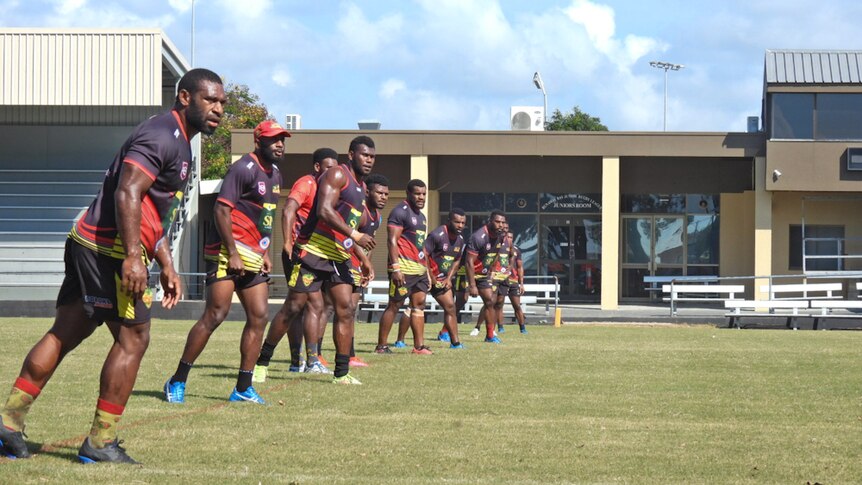 Rugby league players from Papua New Guinea running on a football field.