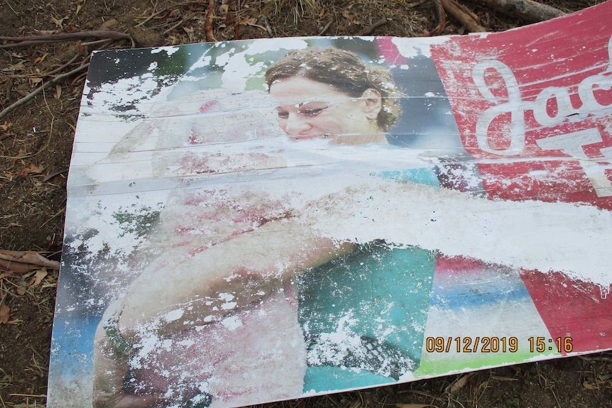 A damaged sign showing a picture of Jackie Trad lies on the ground