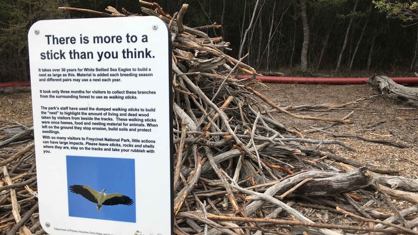 Picture of a sign 'there is more to a stick than you think' with a large pile of sticks behind it