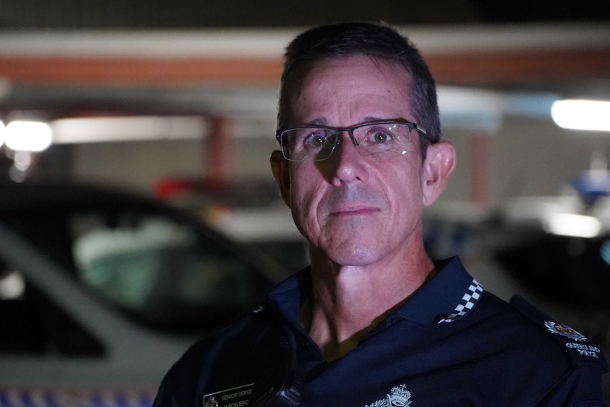 A police officer standing outside at night.