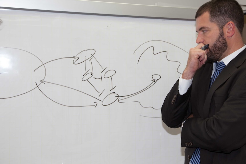 Man in suit standing in front of a whiteboard