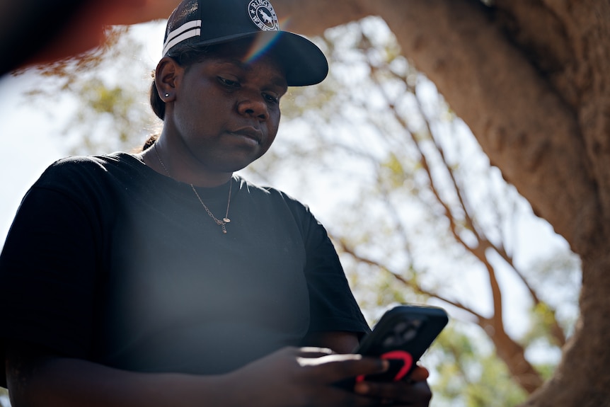 Edwina Murphy lives with type 2 diabetes she sits outdoors wearing a cap while looking at her mobile phone 