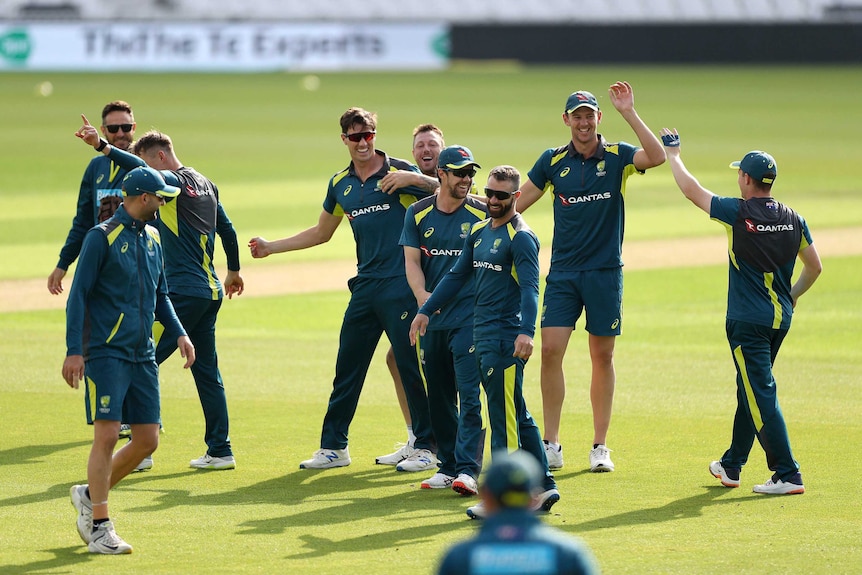 A group of cricketers have a laugh during a training session.