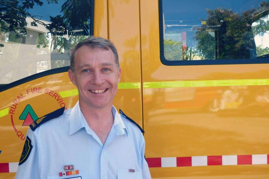 Queensland Rural Fire Brigades Association general manager Justin Choveaux stands in front of a yellow fire truck.