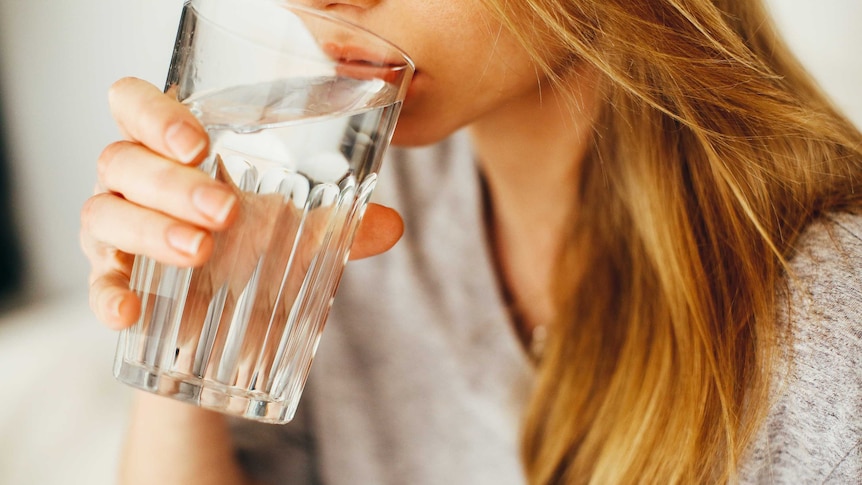 A woman takes a sip from a glass of water