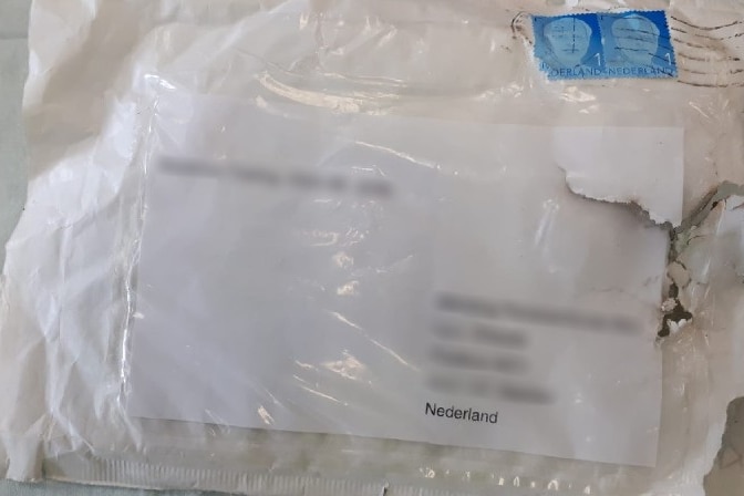 A white parcel partially singed with address blurred out.