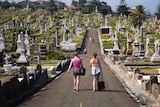 Women walk through a cemetery.