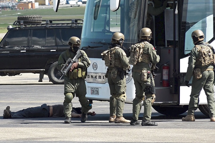 Papua New Guinea Defence Force soldiers stand near the door of a bus.