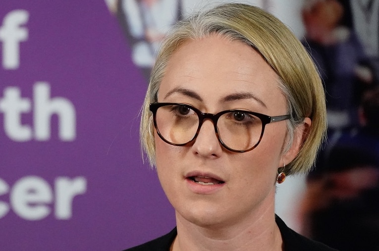 Annaliese van Diemen stands at a lectern during a press conference.