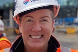 Shelley Goodwin smiles at the camera in a white hardhat and orange high-vis.