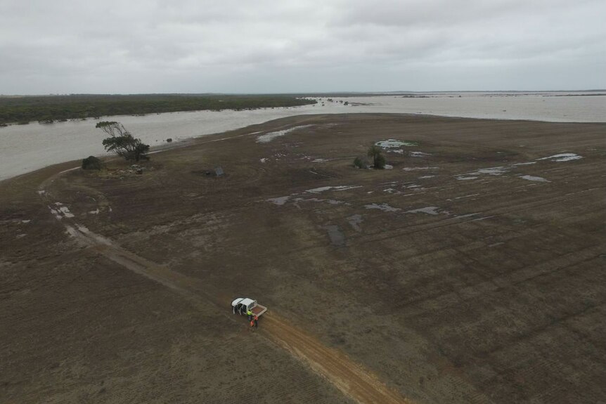 An aerial photo of a ute on land surrounded by floodwater.