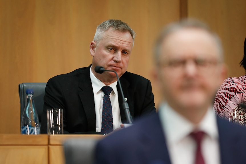 Rockliff looks at Albanese from behind. Albanese is out of focus in foreground.