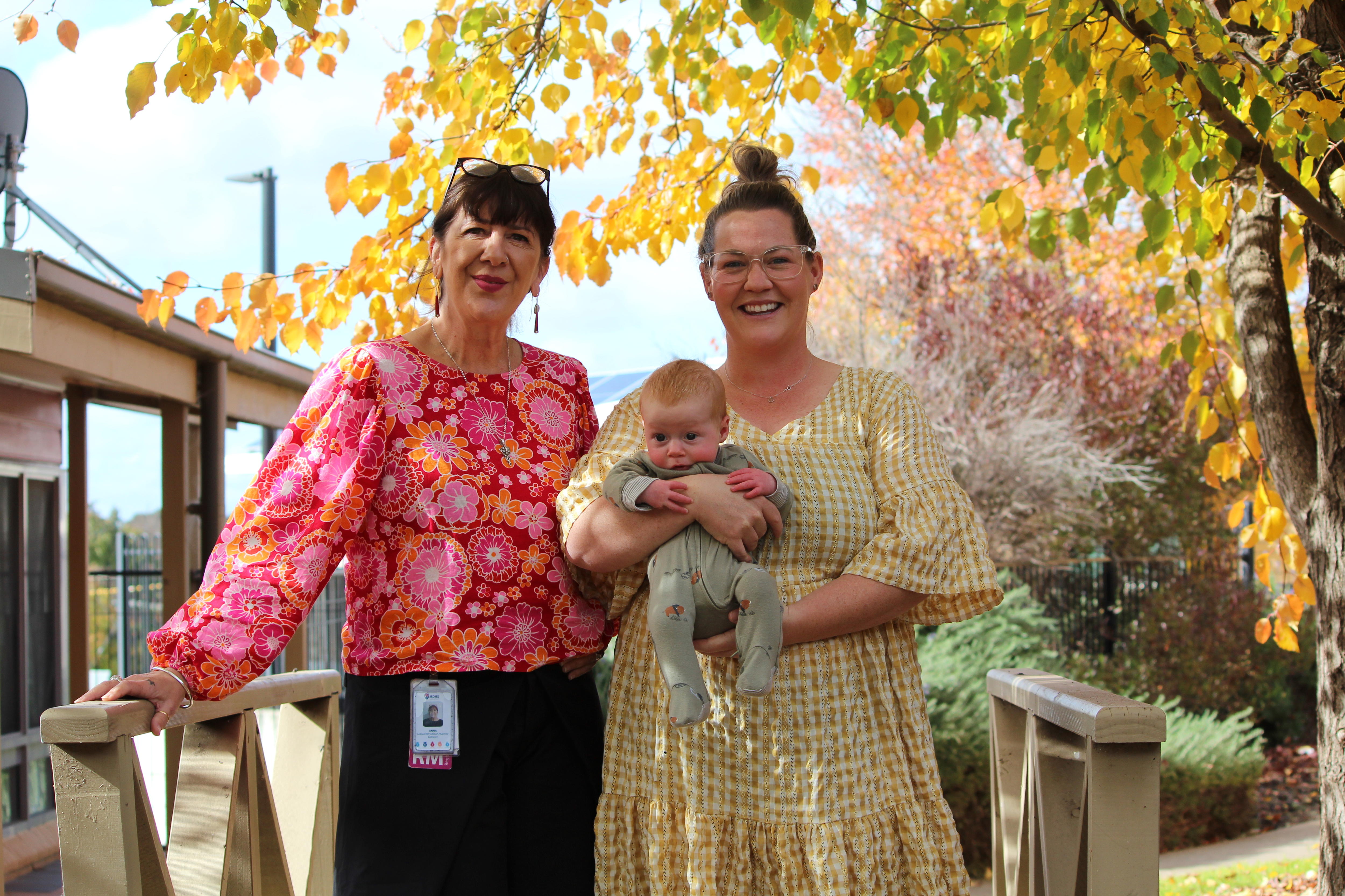 Two women smile holding a baby