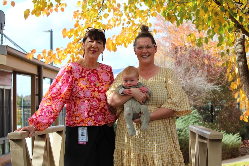 Two women smile holding a baby