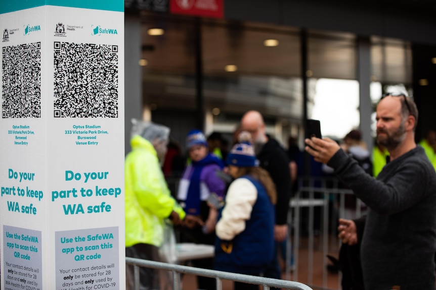 A man uses his phone to scan a Safe WA QR code.