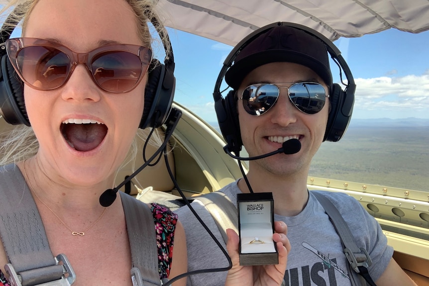 A young couple wear headphones and headsets in an aircraft.