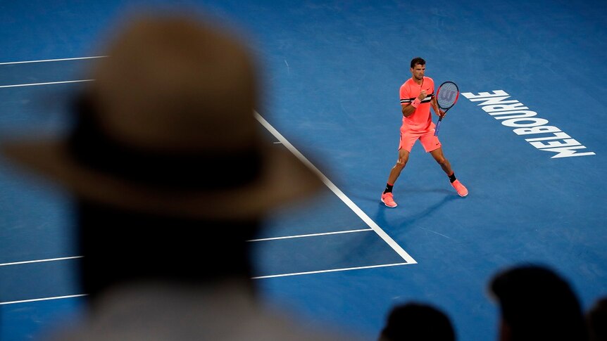 Grigor Dimitrov viewed from a distance raises a fist in celebration after winning a point against Nick Kyrgios