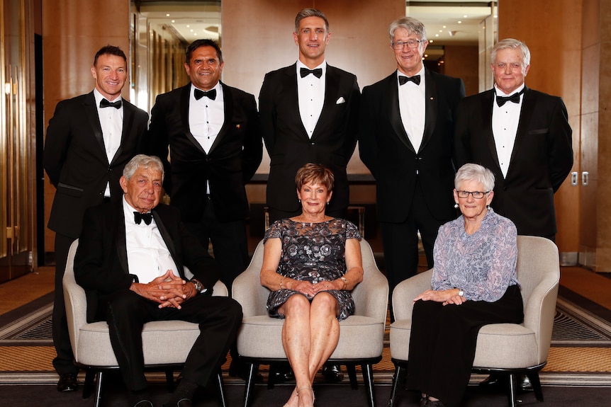 men and women pose at a black-tie event.