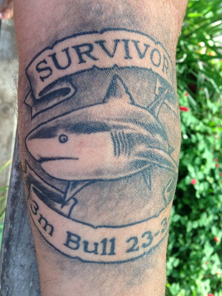 A tattoo has a picture of a shark and says 'Survivor' above and '3m Bull' below
