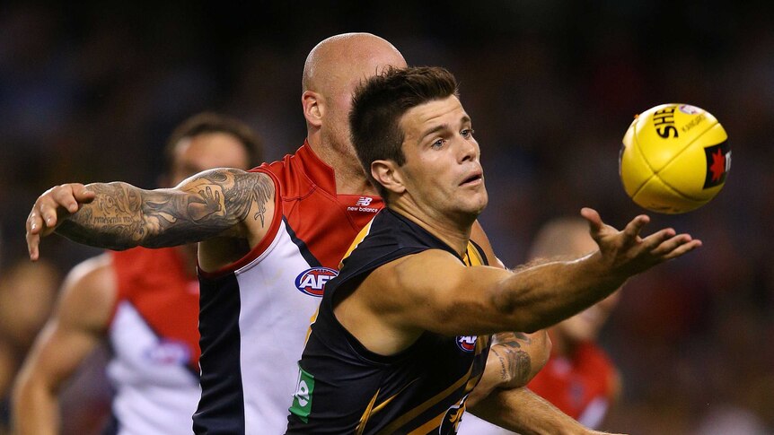 Richmond skipper Trent Cotchin (R) reaches for the ball against Melbourne in February 2013.