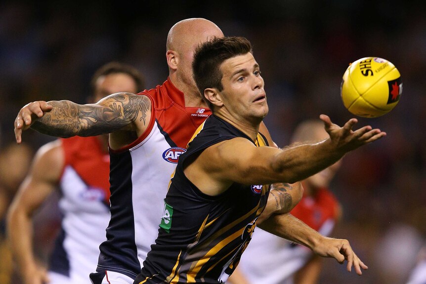 Richmond skipper Trent Cotchin (R) reaches for the ball against Melbourne in February 2013.