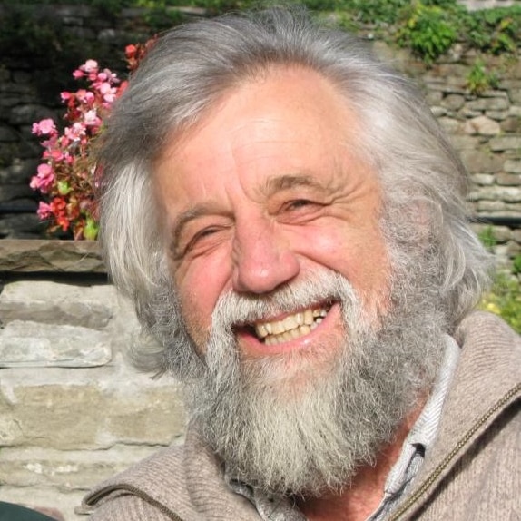 An older man with white hair and a beard holding a rock