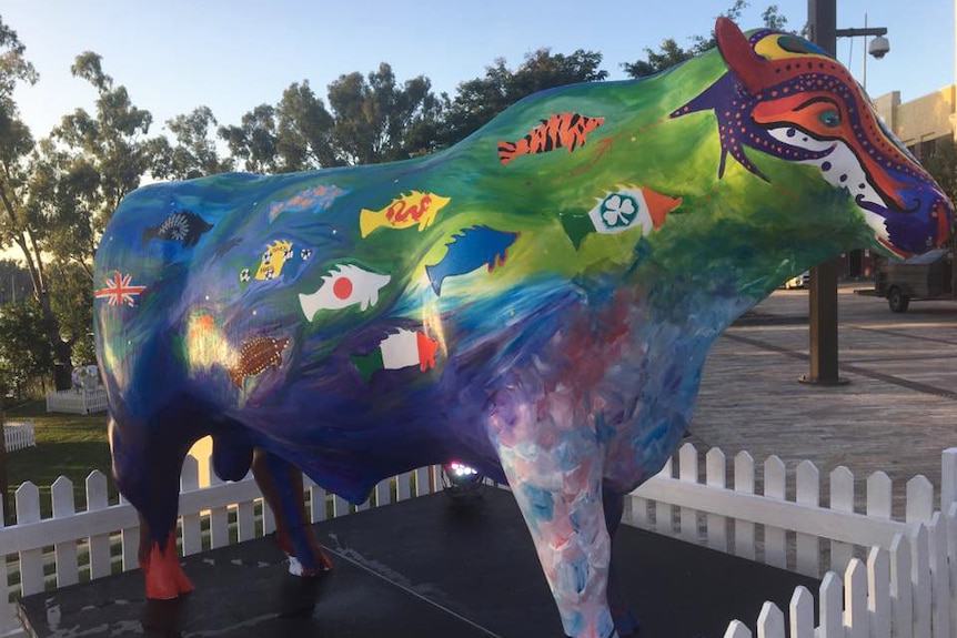 Cow sculpture painted with fish designs showing flags of the world, but with Taiwan flag painted over in blue by council.