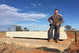 Rob Pearce sits on a water trough at his property