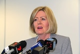 Lisa Scaffidi in front of a bank of media microphones.