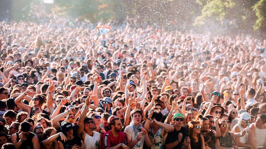 Thousands of people dance in front of a stage.