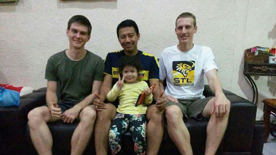 Two Australian men sit with a Malaysian man and his toddler daughter.